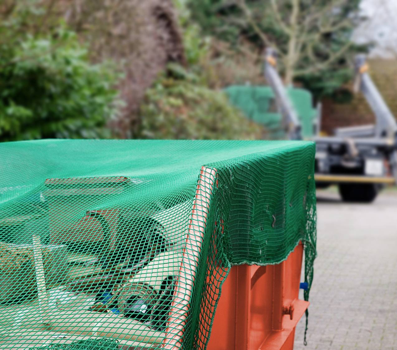 Rotercontainer mit Bauschutt und Netz